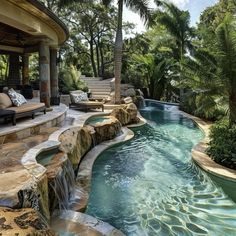 an outdoor swimming pool surrounded by palm trees and water features stone steps leading up to it