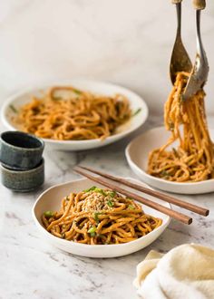 three plates of noodles with chopsticks on the side