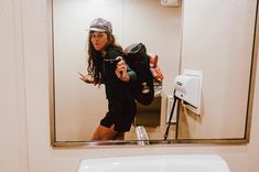 a woman is taking a selfie in the bathroom mirror with her camera and backpack