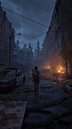 a person walking down a street next to a fire in the middle of a forest