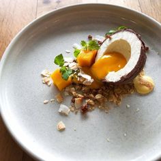 a plate with an egg and other food items on it, sitting on a wooden table