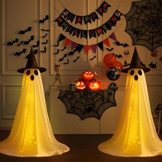 two halloween decorations in the shape of ghost heads and pumpkins on a table with lights