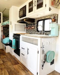 a kitchen with white cabinets and wood flooring next to a wall mounted microwave oven