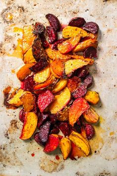 roasted beets and carrots on a sheet of parchment paper with brown stuff all over them