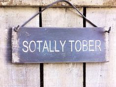 a wooden sign that says totally tober hanging on a door with rope and hooks