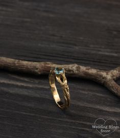 a gold ring with a blue topazte stone sits on a piece of wood