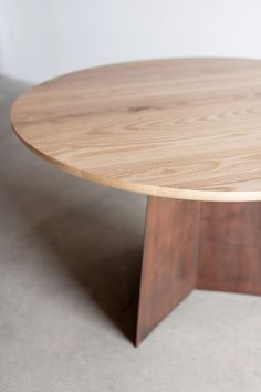 a round wooden table sitting on top of a white floor