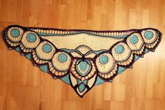 a crocheted doily is hanging on a wooden floor