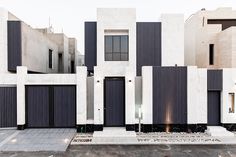 a white and black building with some doors on it's sides in front of other buildings