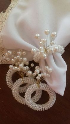 a white satin bag with pearls and brooches on the side, sitting on a table