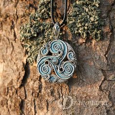 a necklace with an intricate design hanging from it's side on a tree trunk