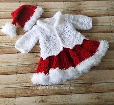 a red and white crocheted outfit with matching hat on top of a wooden floor