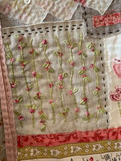 a close up of a piece of cloth with flowers and leaves on it, as well as an embroidered design