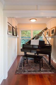 there is a piano in the living room with pictures on the wall and a bench