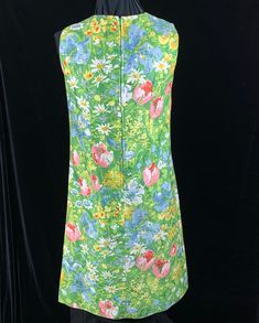 "Wonderful vintage Margaret Smith shift dress from the 1970's when her clothes were in Bonwit Teller and speciality shops across the country. Daisies, tulips and other colorful flowers on a green background. Soft easy care cotton blend fabric. Size 10 Bust: 35-36\" Waist: 34\" Hips: 34-35\" Length: 40.5\" Excellent condition no issues. There is an 1.5\" wide separate belt of the same fabric with this dress. This will be your go to dress for hot weather and resort vacations. Sale supports Vermont Mid-century Floral Print Dress For Spring, Mid-century Floral Print Spring Dress, 1970s Sleeveless Floral Print Dress, 1970s Style Sleeveless Floral Print Dress, Floral Sleeveless, Green Backgrounds, Sundress, Shift Dress, Size 10