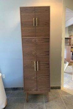 a tall wooden cabinet sitting on top of a tile floor