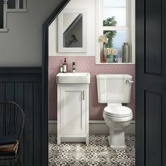 a white toilet sitting under a window next to a sink