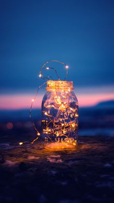 a mason jar filled with fairy lights on top of a rock