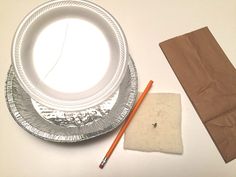 a plate, napkin and pencil on a white table with brown paper bag next to it