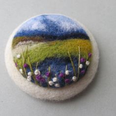 a button with flowers and grass on it