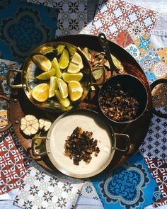 an assortment of food is displayed on a plate with spoons and bowls filled with fruit