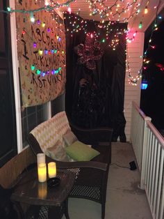 a porch covered in christmas lights and decorations with candles on the table next to it