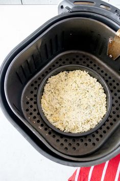 a bowl filled with rice sitting on top of a red and white table cloth next to a black frying pan