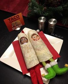 two christmas themed burritos on a plate with elf's legs and stockings