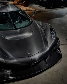 a black sports car is parked in a garage with its hood up and it's shiny