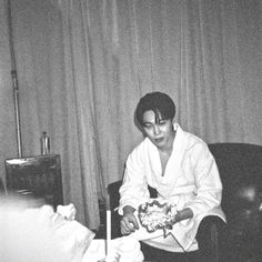 black and white photograph of woman in robe sitting on chair