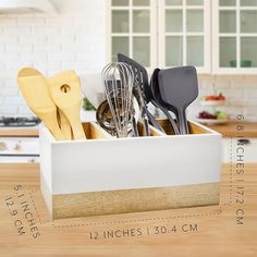 the kitchen utensils are organized in a white box on top of a wooden table