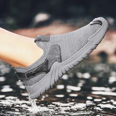 a person's foot in the water wearing grey shoes