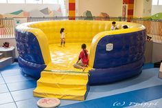 two children are playing in an inflatable water slide at the indoor play area