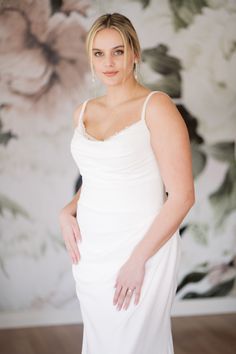 a woman in a white dress posing for the camera with her hands on her hips