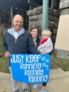 a man and woman holding a blue sign that says just keep running