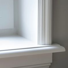 the corner of a white shelf with a window on it's side and a light coming from behind