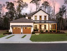 a large white house with two garages and trees in the background at sunset or dawn