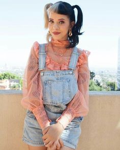 a woman in denim overalls posing for the camera with her hands on her hips