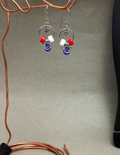 a pair of red, white and blue earrings are hanging from a wire on the floor