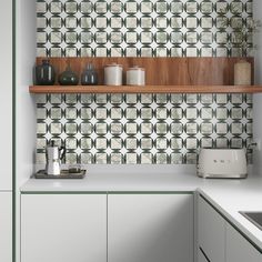 a kitchen with green and white tiles on the wall, shelves above the stove top