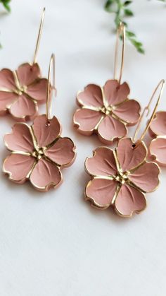 four pink flower shaped earrings sitting on top of a table