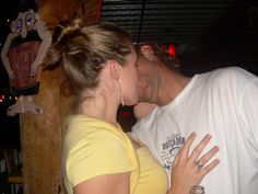 a man and woman kissing each other in a bar