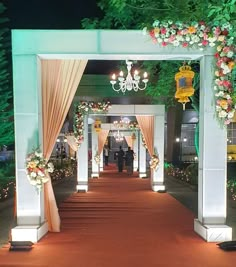 an outdoor wedding ceremony with flowers and chandeliers on either side of the aisle