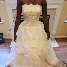 a woman in a white wedding dress standing on a hard wood floor next to a fireplace