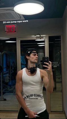 a man taking a selfie in front of a mirror wearing headphones and holding a cell phone