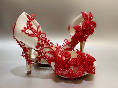 a pair of red and white high heels with flowers on the heel, decorated with beads