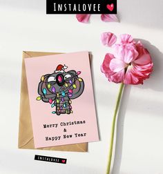 an elephant christmas card next to pink flowers