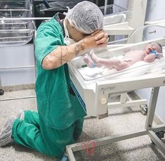 a man in green scrubs kneels next to a baby