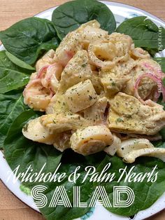 a plate filled with pasta and spinach on top of a leafy green table