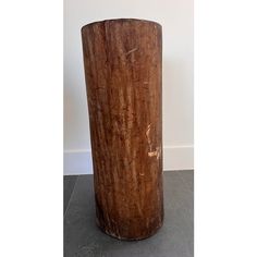 a large wooden vase sitting on top of a cement floor next to a white wall